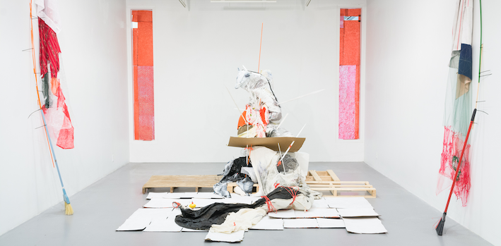 Art exhibit of room with zip tied cleaning and packing supplies