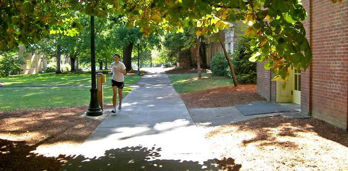 A student running under shady trees