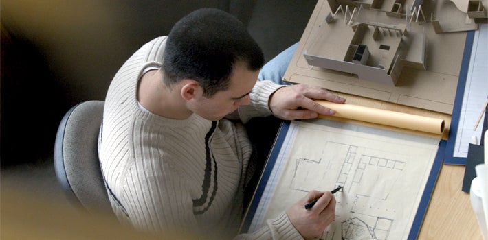 A male student draws an architectural blueprint.