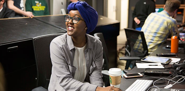 Female student drinking coffee and smiling while working in Allen Hall