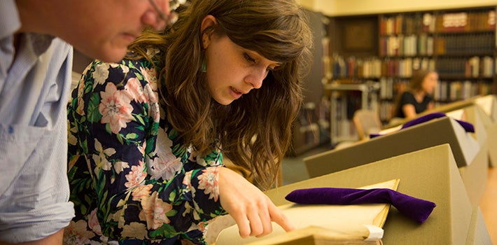 Female student reading a Latin or Greek text with a professor