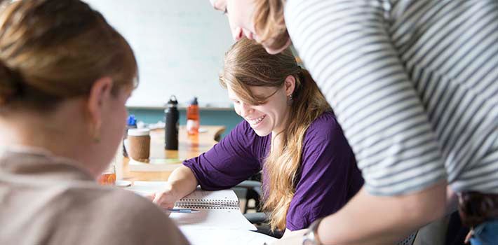 Female student smiles as female professor assists with her studying.