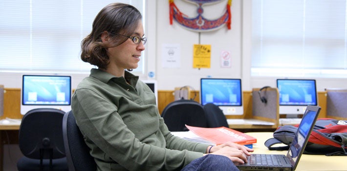 Female student types away on her laptop in a computer lab.