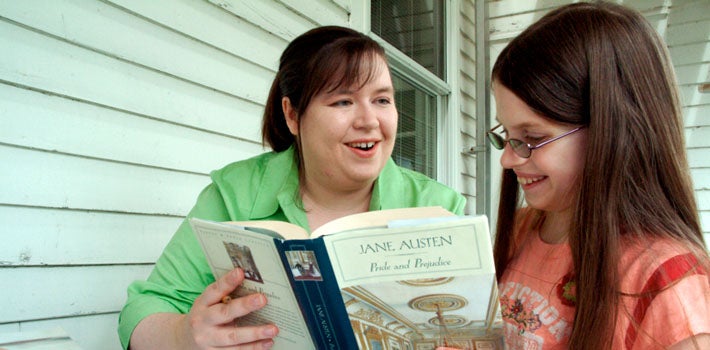 An adult reading 'Pride and Prejudice' to a little girl.