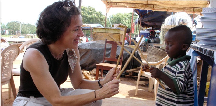 A person playing games with sticks with a child in a different country.