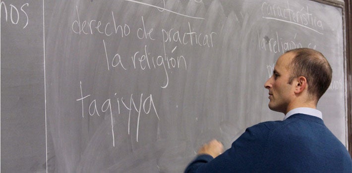 Professor lecturing  in Spanish using a chalkboard 